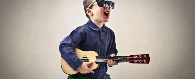 A kid singing enthusiastically with his little guitar